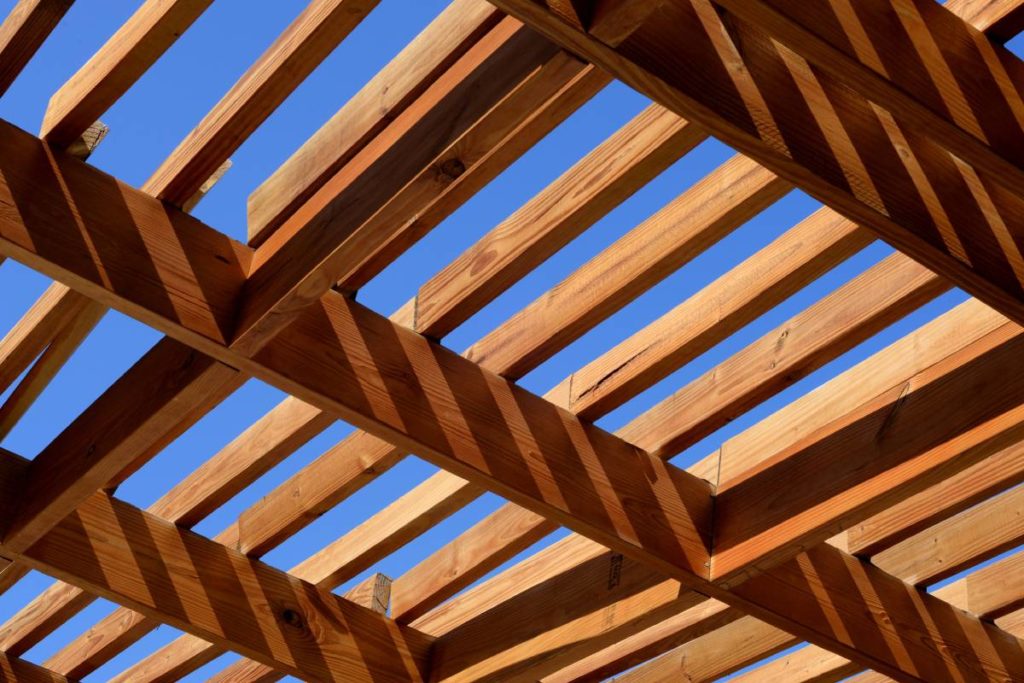 sun shining on a wooden pergola roof