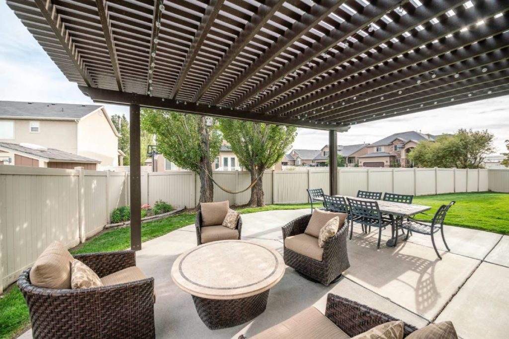 A fenced backyard with new patio furniture and a pergola patio cover